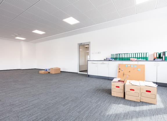 Empty modern office space with fresh white painted walls, carpet flooring, boxes, and cabinets.